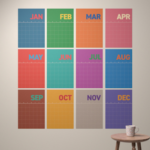 May include: A collection of twelve wall calendars, one for each month from January to December. Each calendar is a different bright colour with a grid pattern. The months are written in bold, uppercase letters. A small wooden table with a mug is in the bottom right corner.