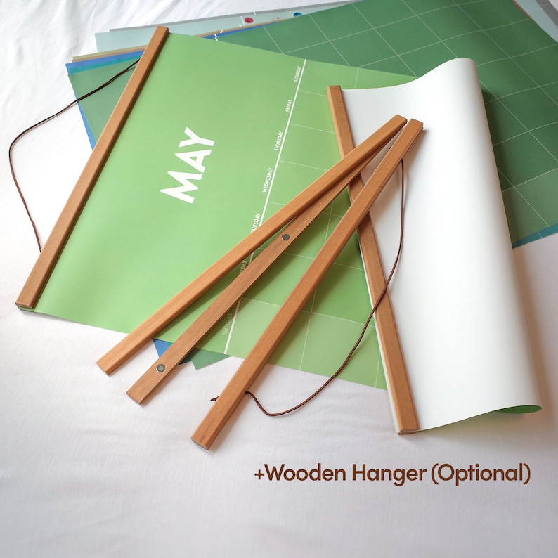 May include: A green calendar with the word "MAY" printed on it. The calendar is rolled up and has a wooden hanger attached to it. The hanger is optional.