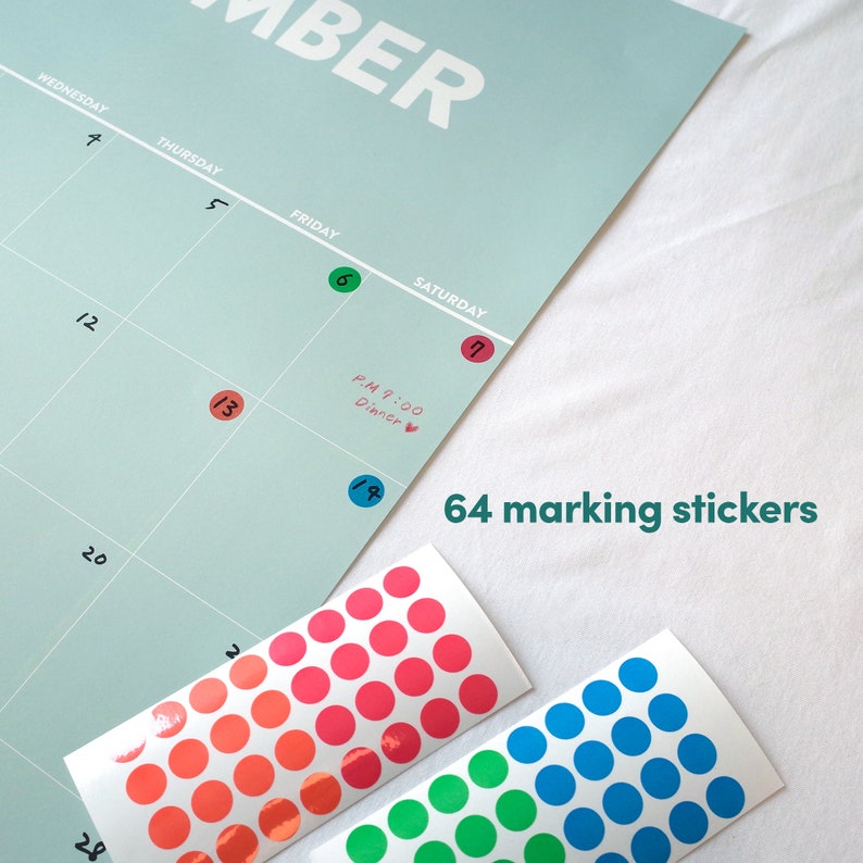May include: A set of 64 colorful round stickers for marking a calendar. The stickers are in three colors: red, blue, and green. The stickers are shown on a sheet of paper with a calendar printed on it. The calendar has the word "November" at the top and the days of the week listed across the top. The calendar has dates written in black ink. The stickers are arranged in rows and columns on the sheet of paper. The text "64 marking stickers" is written in black ink on the sheet of paper.