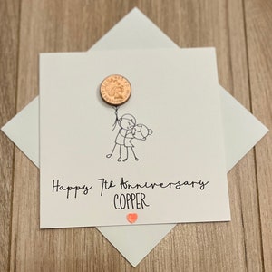 May include: A white anniversary card with a copper penny attached as a balloon. The card features a stick figure couple and the text "Happy 7th Anniversary COPPER" with a small orange heart.