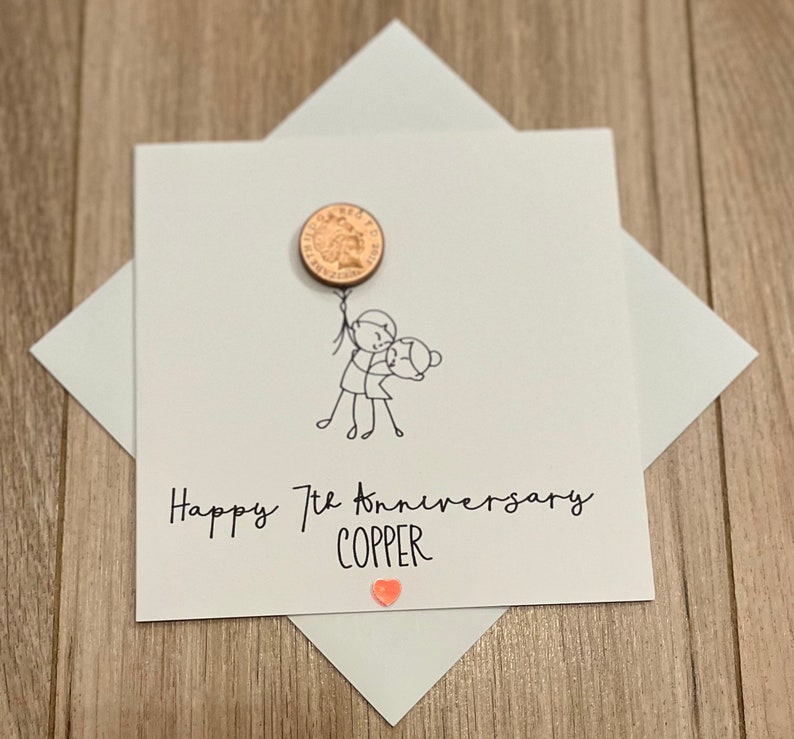 May include: A white anniversary card with a copper penny attached as a balloon. The card features a stick figure couple and the text "Happy 7th Anniversary COPPER" with a small orange heart.