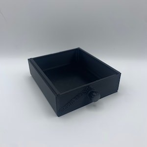 Könnte beinhalten: Eine kleine schwarze Schublade mit einem Knopf an der Vorderseite. Die Schublade ist mit dem Text "@SUPERFRRPANDA" beschriftet.