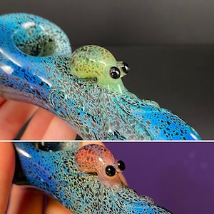 May include: A glass pipe shaped like an octopus with a blue and green speckled design. The octopus has black eyes and a light green body.