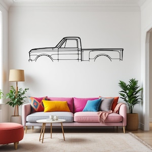 Puede incluir: Un dibujo en blanco y negro de una camioneta vintage en una pared blanca sobre un sofá gris claro con almohadas de color rosa, amarillo y azul.