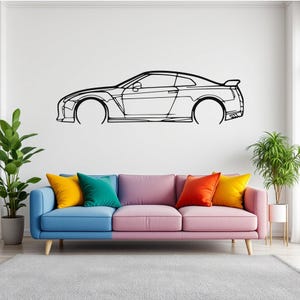 Könnte beinhalten: Eine Schwarz-Weiß-Zeichnung eines Sportwagens an einer weißen Wand über einem bunten Sofa mit Kissen.