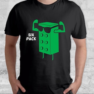 May include: Black t-shirt featuring a green cartoon character flexing its muscles. The character is a block with a face and sunglasses. The text "SIX PACK" is printed below the character.