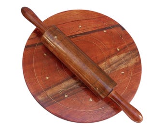 Puede incluir: Un rodillo de madera y una tabla redonda de madera con un diseño decorativo. La tabla tiene un patrón circular con acentos dorados.