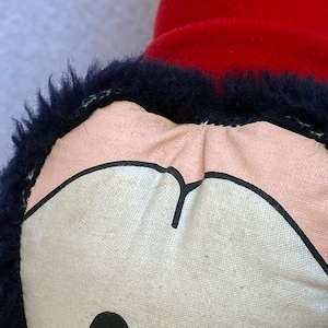 May include: Close-up of a plush toy with a black fur trim and a pink and white face. The face has a black outline and a black nose.
