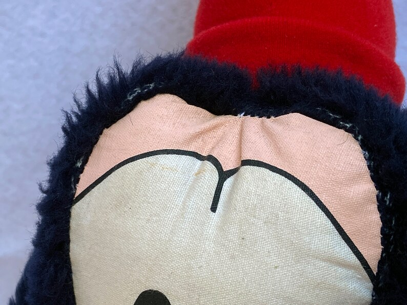May include: Close-up of a plush toy with a black fur trim and a pink and white face. The face has a black outline and a black nose.
