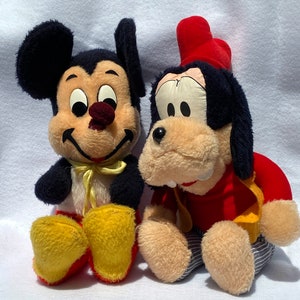 May include: A vintage plush Mickey Mouse and Goofy toy set. Mickey Mouse is wearing a yellow bow tie and red shoes. Goofy is wearing a red hat and a red and yellow shirt.