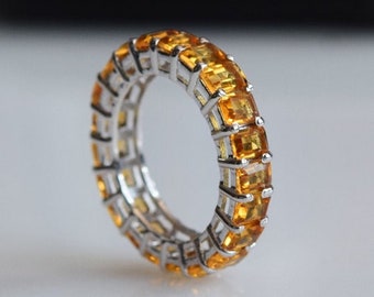 May include: A silver band ring with a row of square-shaped orange gemstones.