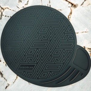 May include: Black and gray geometric patterned silicone coaster with a raised edge and a separate black silicone mouse pad with a textured surface. The coaster has the text "DEBOWLER" printed on it.