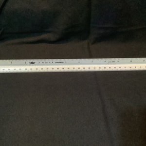 May include: A white and gray engineer's ruler with both imperial and metric measurements. The ruler is marked with numbers and lines for precise measurements. The ruler is 12 inches long.