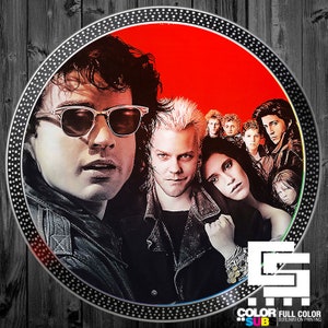 May include: A red and black vinyl record featuring a group of people from the movie "The Lost Boys". The record is a circular disc with a black border and a white label with the text "Color Sub Full Color Sublimation Printing".