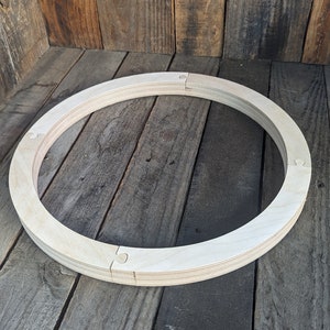 May include: A wooden circle made of multiple pieces of wood, with a puzzle-like design. The circle is about 10 inches in diameter and is sitting on a wooden surface.