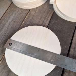 May include: A set of three ceramic mugs with a speckled, cream-colored glaze. Each mug features a different hand-painted floral design in shades of blue, green, and yellow. The mugs have a simple, rounded shape.