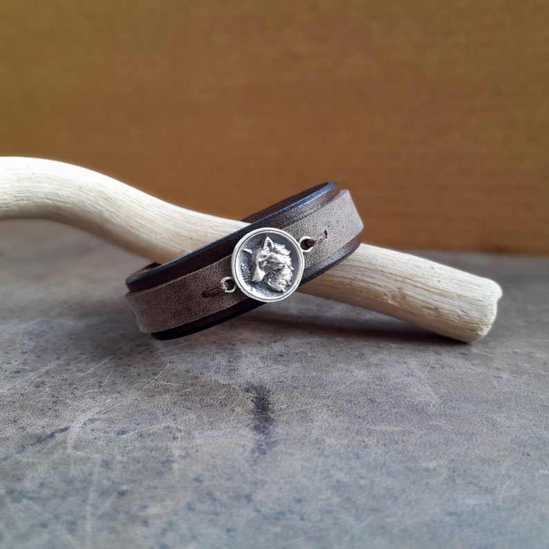 A handmade chestnut brown leather bracelet featuring a hand crafted antique silver 925 white wolf pendant.