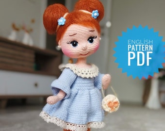 May include: A handmade crochet doll with ginger hair in buns, wearing a light blue dress with white lace, orange tights, and white shoes. The doll has a small purse and blue flower hair accessories. The image includes the text "ENGLISH PATTERN PDF".