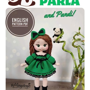 May include: Crochet doll pattern for Parla and Pandi. The doll is wearing a green dress with black trim and black shoes. The doll has brown hair and a green bow. The pattern is available in English.