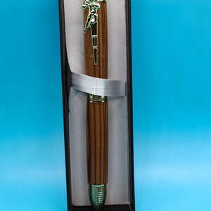 May include: A wooden pen with a gold-toned top and bottom. The pen is in a black box with a white ribbon.