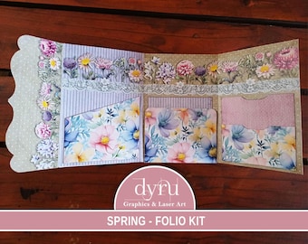 Peut inclure: Un kit folio sur le thème du printemps avec des motifs floraux et une bordure en dentelle. Le kit comprend des poches et des compartiments pour organiser et ranger des articles. Le kit est étiqueté "Spring - Folio Kit" et "dyru Graphics & Laser Art".