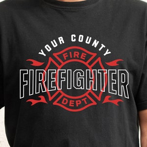 May include: A black t-shirt featuring a white graphic design of a firefighter's cross with flames. The text "YOUR COUNTY FIRE FIREFIGHTER DEPT" is on the graphic. The text "FONT INCLUDED for COUNTY, CITY, or TOWN" is at the bottom of the image. The text "MIDDAY SVG" is in a yellow box at the bottom left of the image. The text "SVG, PNG, EPS, DXF premium cut files" is in a white box at the bottom centre of the image. The text "No. 1796" is in a yellow box at the bottom right of the image.
