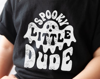 May include: A black t-shirt with a white graphic of a ghost with the text "Spooky Little Dude" in a distressed font.