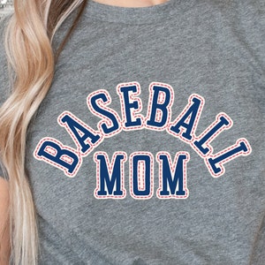 May include: Gray t-shirt with a blue and red stitched design that says "BASEBALL MOM" in a varsity style font.