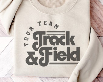 May include: A beige sweatshirt with the text "Your Team Track & Field" in a retro font style. The text is in a circle with a line across the top and bottom. The font is included for use with the Mascot software.