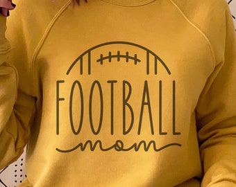 May include: A yellow sweatshirt with the text "FOOTBALL mom" and a stylised football graphic. The text is in a brown colour.