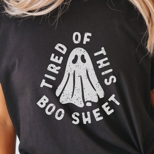 May include: A black t-shirt with a white graphic of a ghost and the text "Tired of this boo sheet".
