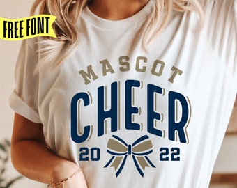Może przedstawiać: Biała koszulka z nadrukiem w kolorze granatowym i złotym, na którym widnieje napis "Mascot Cheer 20 22" ze złotą kokardką w środku.