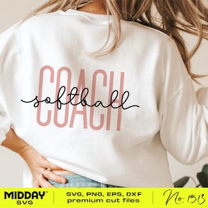 May include: A white sweatshirt with the text "COACH softball" in pink lettering on the back. The text is in a cursive font. The sweatshirt is being worn by a person.