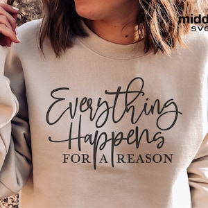 May include: A beige sweatshirt with the text "Everything Happens For A Reason" in black cursive lettering.