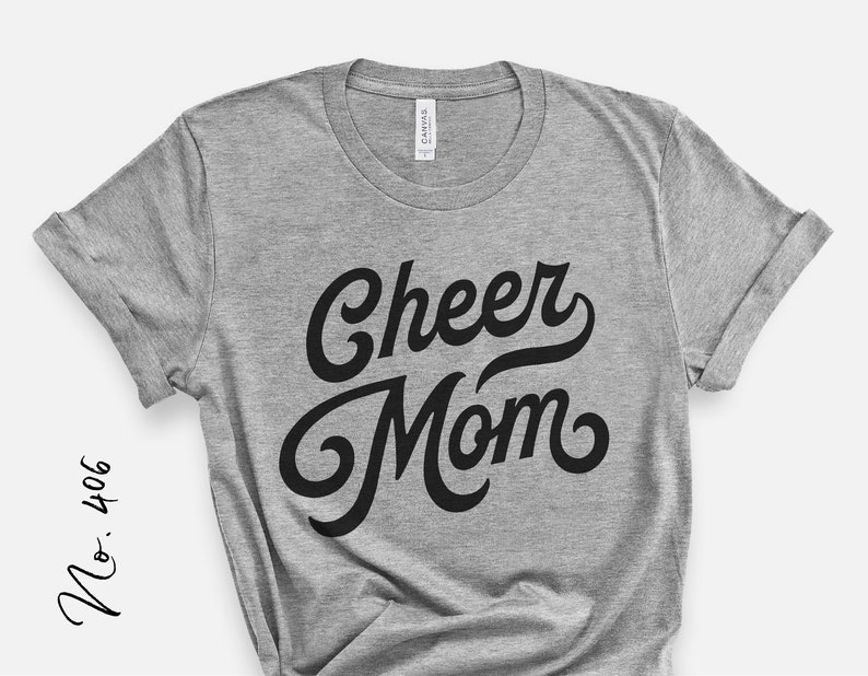 Puede incluir: Camiseta gris con texto negro que dice "Cheer Mom" en una fuente retro.
