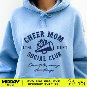 May include: Light blue hoodie with a navy blue graphic that says "Cheer Mom Athl. Dept. Social Club" with a megaphone and a cheerleading pom-pom. The text below the graphic says "Cheer talk, among other things".
