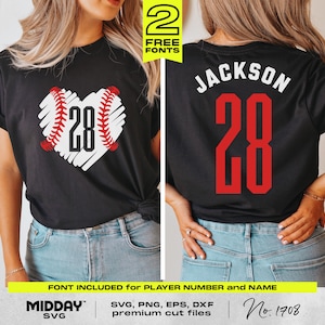 May include: A black t-shirt with a white heart-shaped baseball design and the number 28 inside. The back of the shirt has the name "JACKSON" and the number 28 in red. The shirt is being modeled by a person wearing blue jeans.