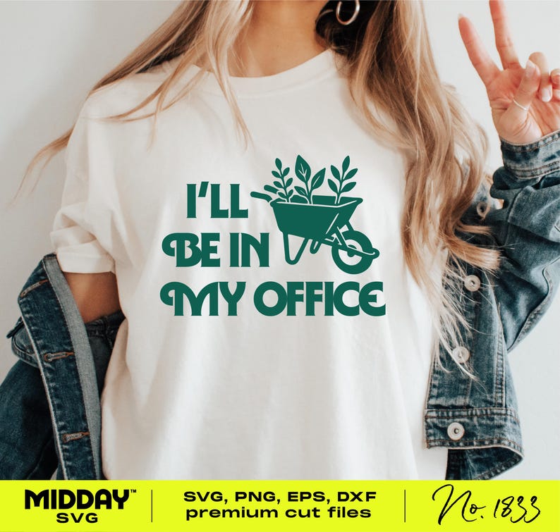 May include: A cream-coloured t-shirt featuring the text "I'll be in my office" in dark green, accompanied by a wheelbarrow graphic filled with plants. The design also includes the words "MIDDAY" and the number "No. 1833".