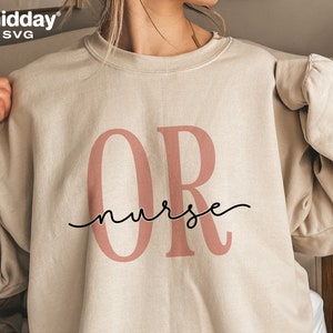 May include: A beige sweatshirt with the letters "OR" in pink and the text "nurse" in black cursive script.
