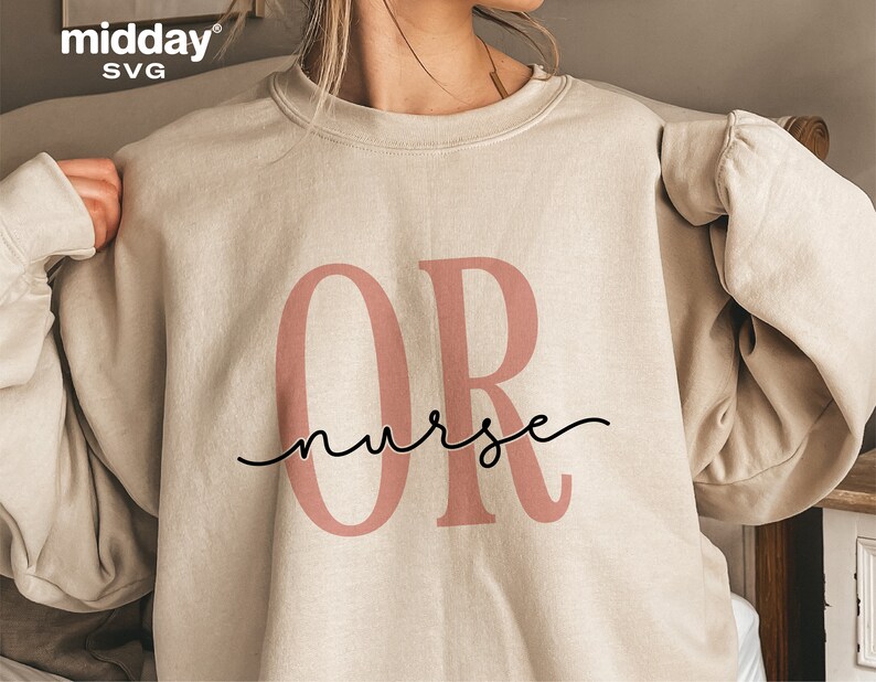May include: A beige sweatshirt with the letters "OR" in pink and the text "nurse" in black cursive script.
