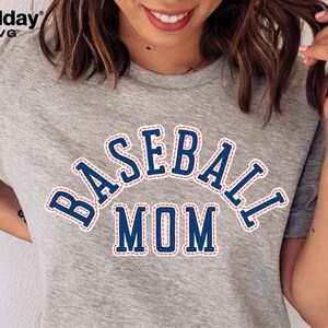 May include: A gray t-shirt with a blue and red baseball mom graphic. The graphic has a stitched look with a white outline.