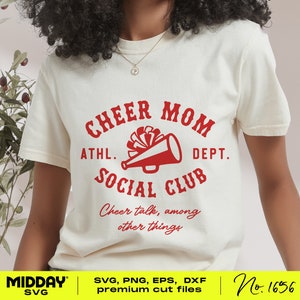 May include: White t-shirt with a red graphic that says "Cheer Mom Athl. Dept. Social Club" with a megaphone and pom poms. The text below says "Cheer talk, among other things".