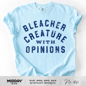 May include: Light blue t-shirt with the text "BLEACHER CREATURE WITH OPINIONS" in dark blue. The shirt has a crew neck and short sleeves. The design is a distressed, vintage style.