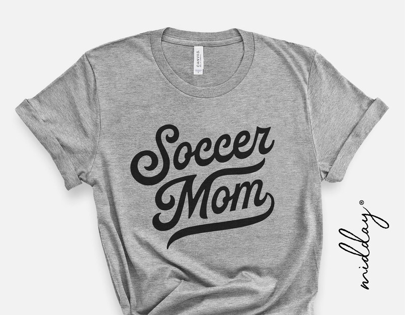 Może przedstawiać: Szara koszulka z czarnym napisem "Soccer Mom" w retro czcionce.