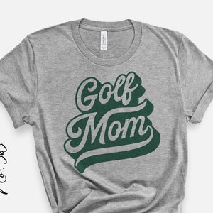 Op de afbeelding: Grijs T-shirt met de tekst "Golf Mom" in groene letters.