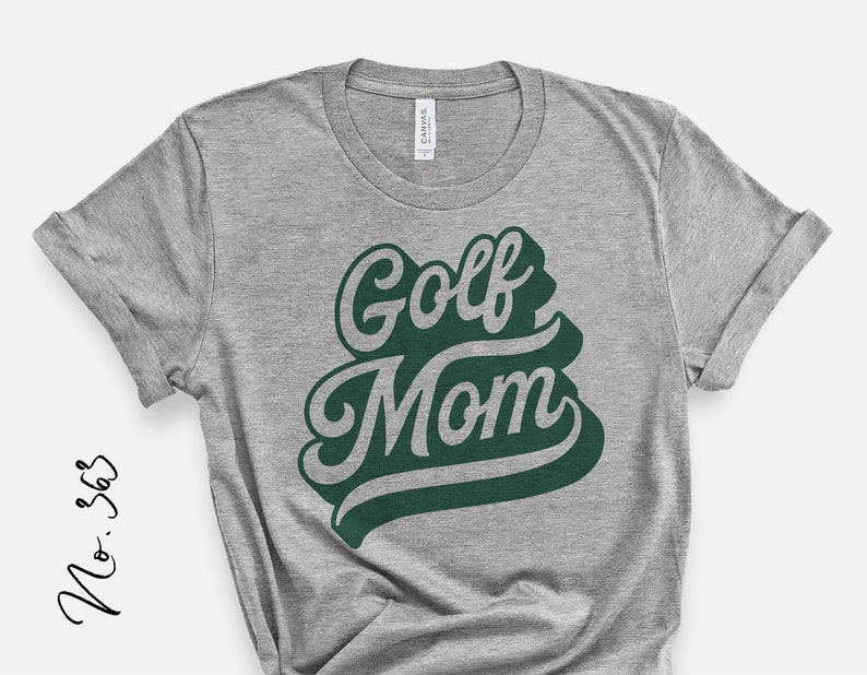 Op de afbeelding: Grijs T-shirt met de tekst "Golf Mom" in groene letters.