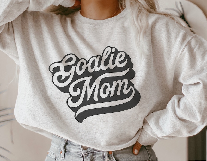 May include: A gray sweatshirt with the text "Goalie Mom" in black, retro-style lettering.