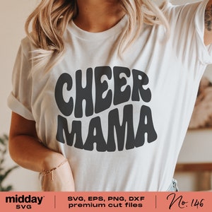 May include: White t-shirt with black text that reads "CHEER MAMA" in a retro font style. The text is in a rounded shape.