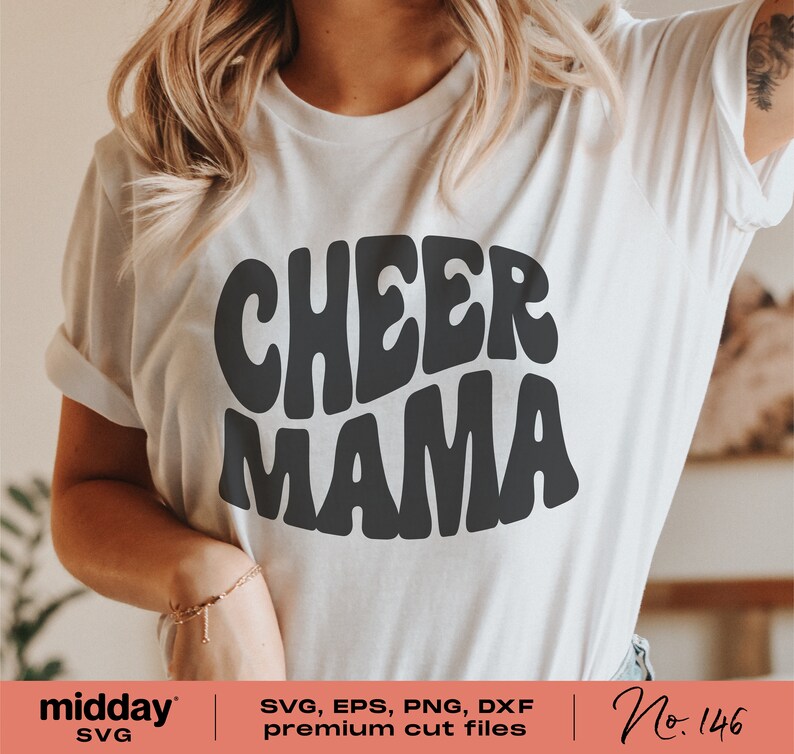 May include: White t-shirt with black text that reads "CHEER MAMA" in a retro font style. The text is in a rounded shape.