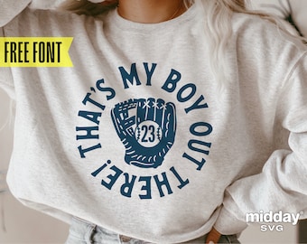 Könnte beinhalten: Ein graues Sweatshirt mit einer blauen Grafik, auf der "That's My Boy Out There!" steht, mit einem Baseballhandschuh und einem Ball in der Mitte. Der Ball hat die Nummer 23.